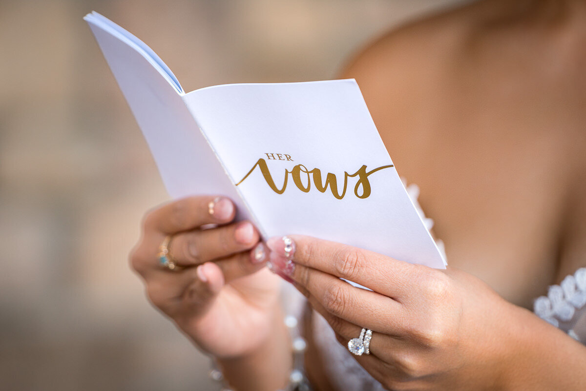 The bride shares a heartfelt and private moment, reading her vows to the groom in front of the elegant backdrop of Casa Real, capturing the love and emotion of their special day.