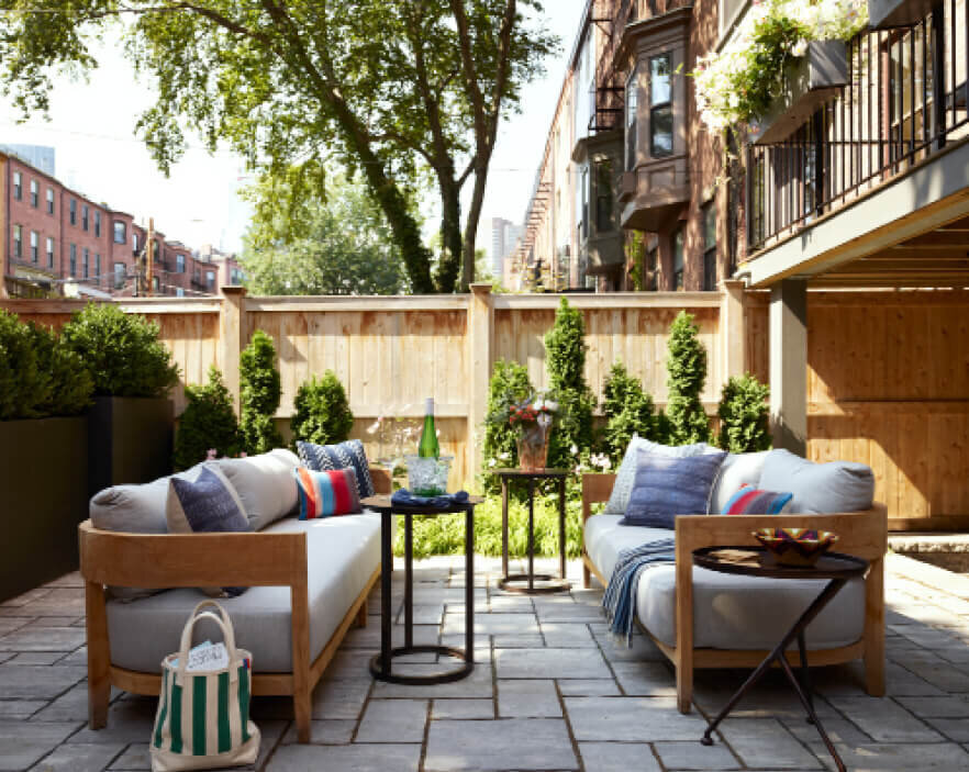 Boston Interior Designer designed an outdoor patio space with modern teak furniture and bright pillows in a brownstone renovation project.