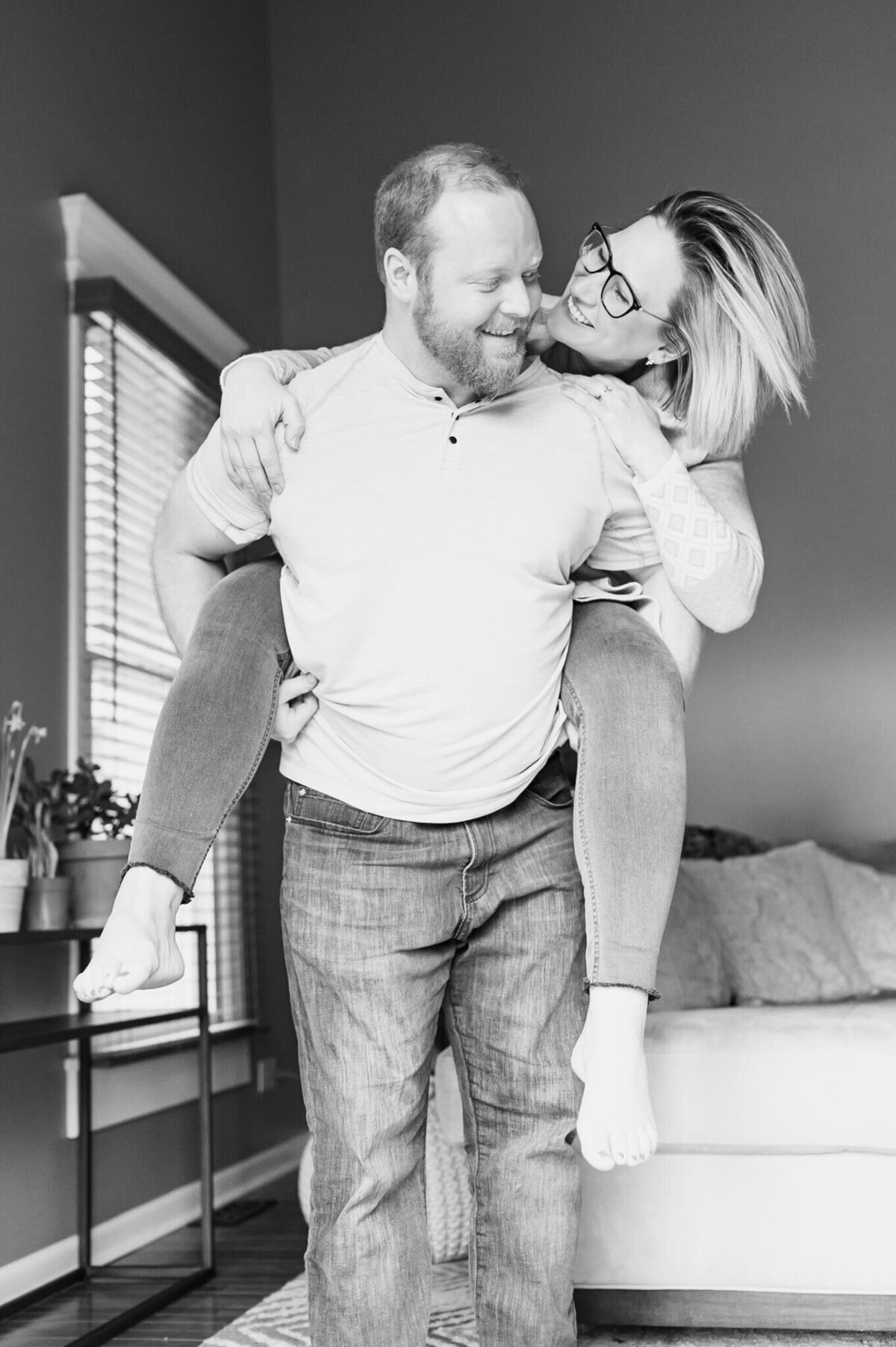 Man giving woman a playful piggy back ride during an in home couples photography session near Chicago, IL.