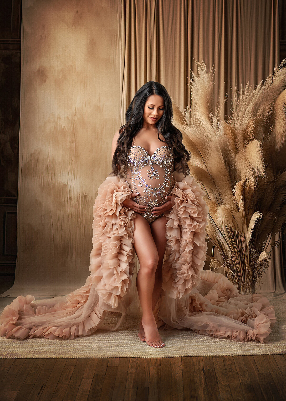 Stunning mom expecting her 1st baby in Phoenix maternity studio, wearing a jeweled bodysuit and fluffy tan robe surrounded by boho decor