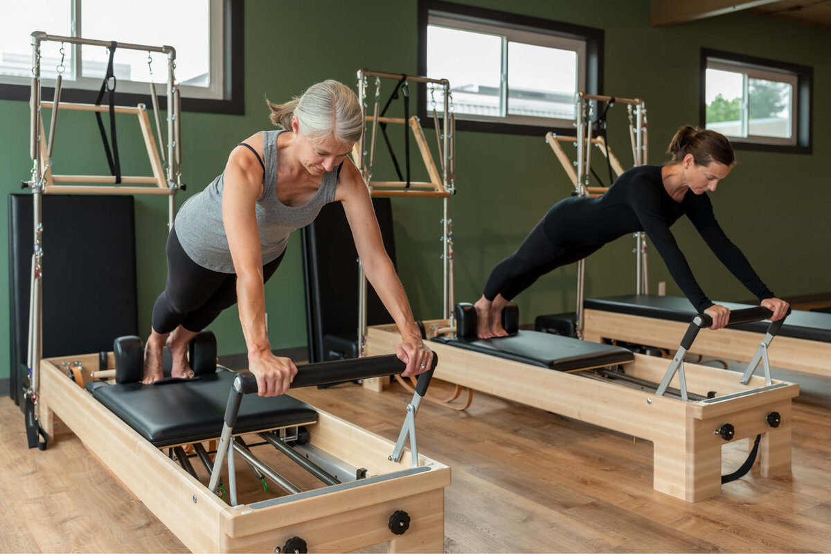 Two women doing the long stretch at Milwaukie Pilates