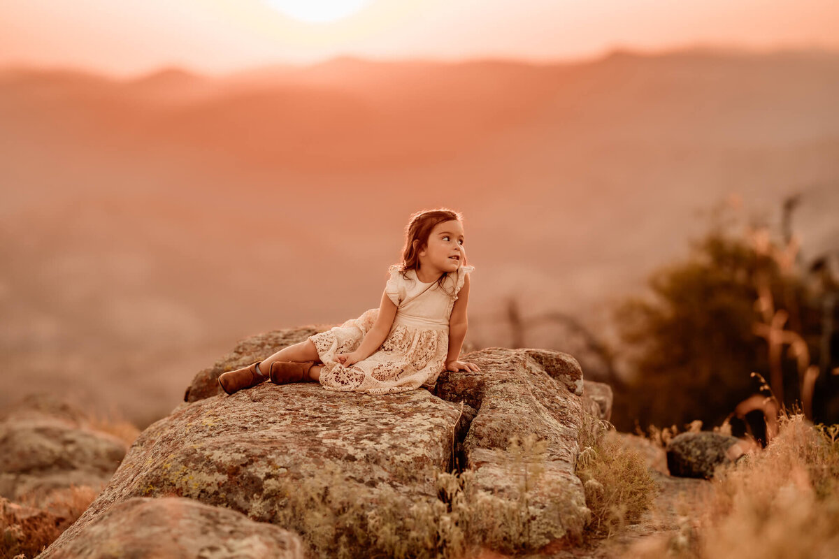 Little girl posed for the sunset on a rock.