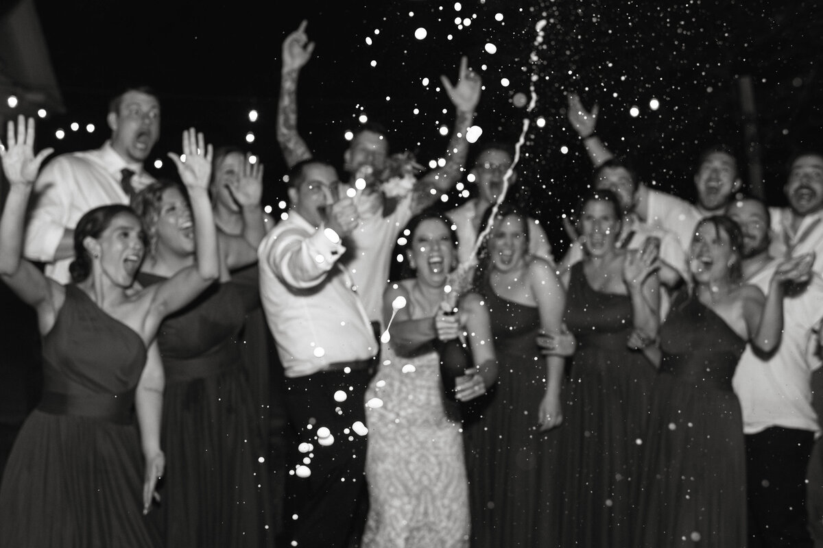 Wedding Party shakes a bottle of Champagne during the reception