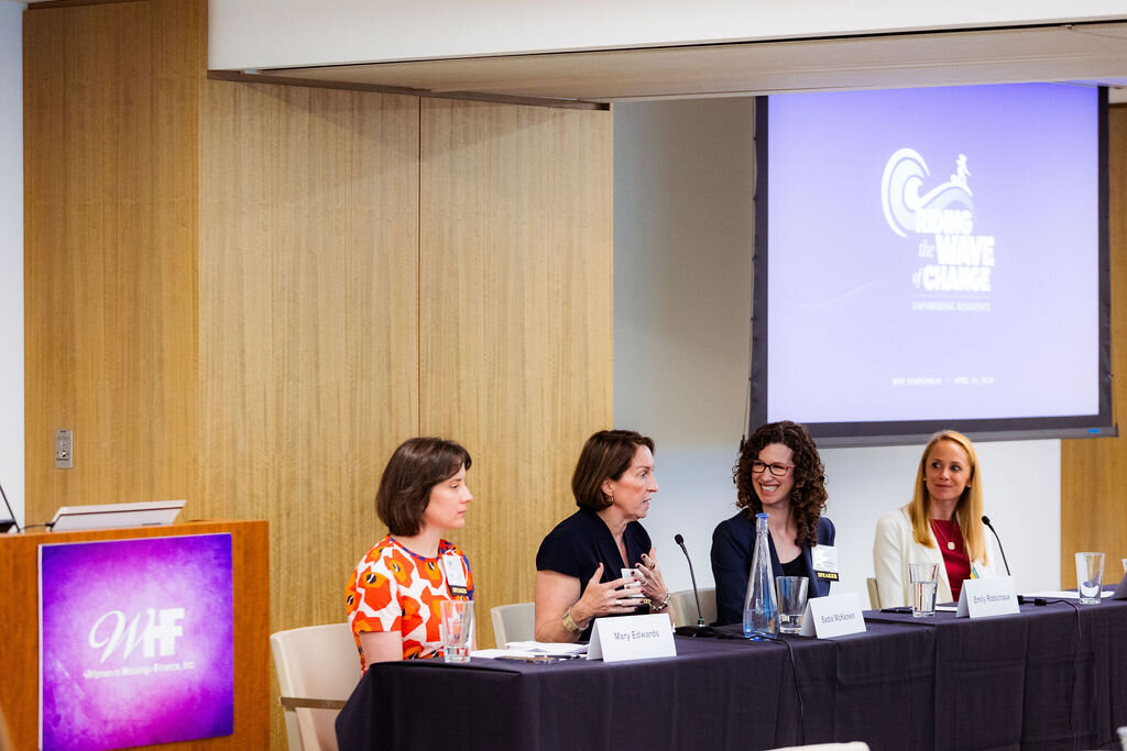 Four people sit at a table for a panel.