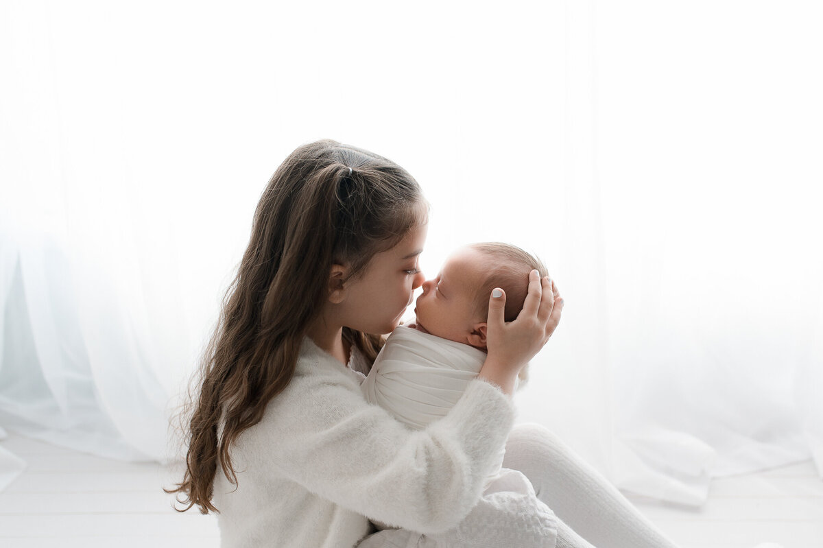 Sibling holding newborn studio session natural light