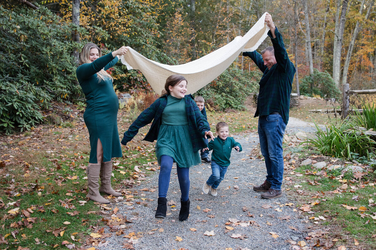 Family of 5 with kids running under a blanket as mom and dad hold it up