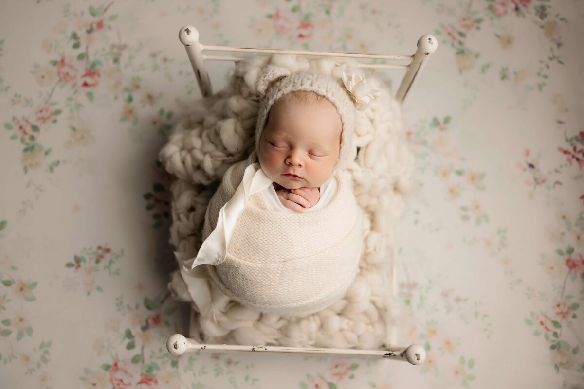 Beautiful baby girl wrapped up laying on a little bed