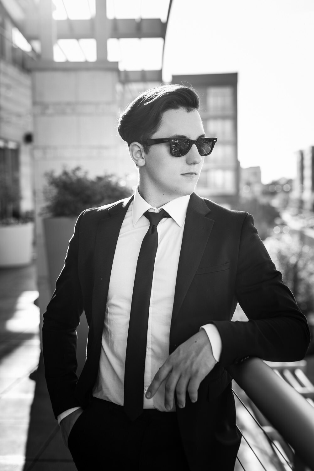 Stylish outdoor portrait of a well-dressed man leaning on a rail with editorial flair.