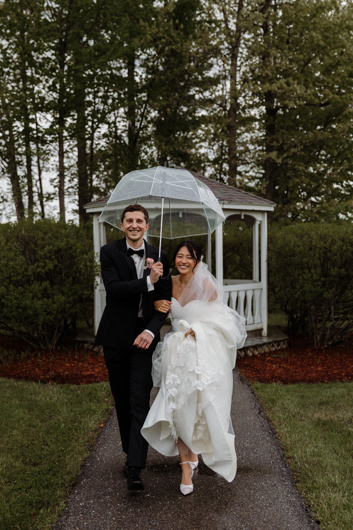 A rainy New England wedding day in Vermont as the bride and groom walk with umbrellas. The day turned into one of the most romantic and scenic days for this beautiful couple.