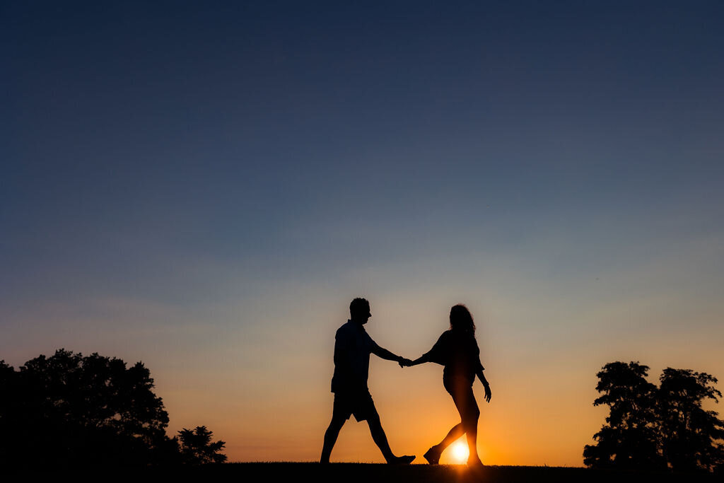 The silhouette of a couple holding hands and walking