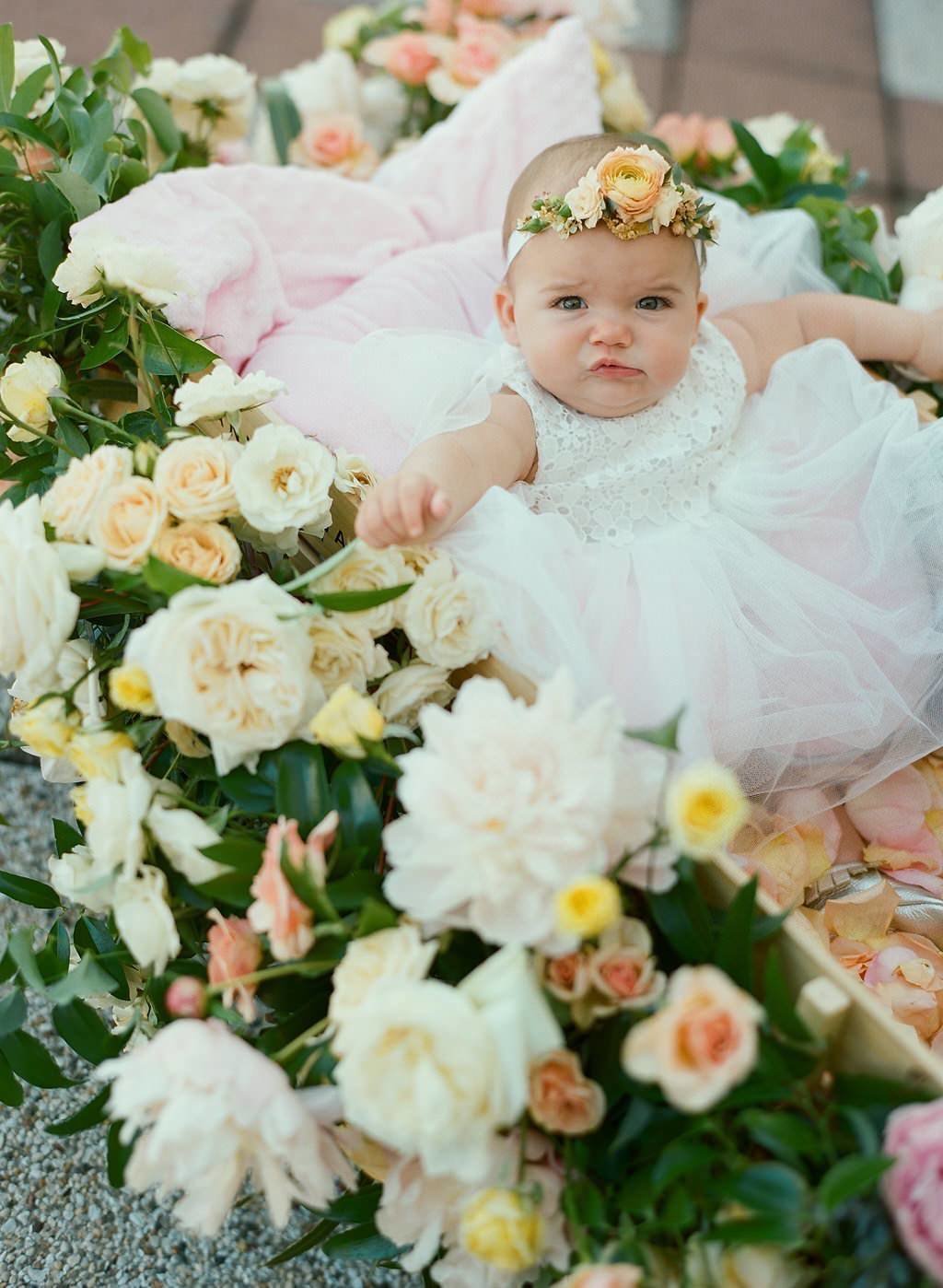 Baby in wedding on flower wagon wearing  flower crown
