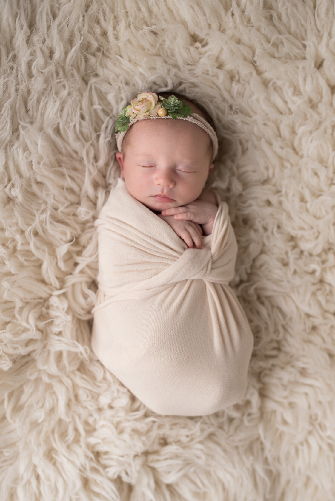 Wrapped newborn in cream  colored furry background