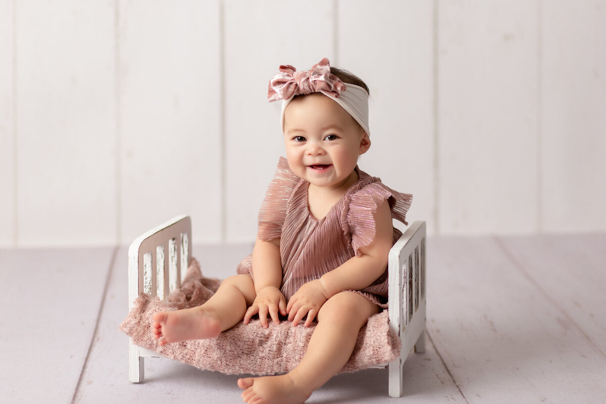 6 Month old baby sitting in tiny bed for photo session in Santa Clarita Studio