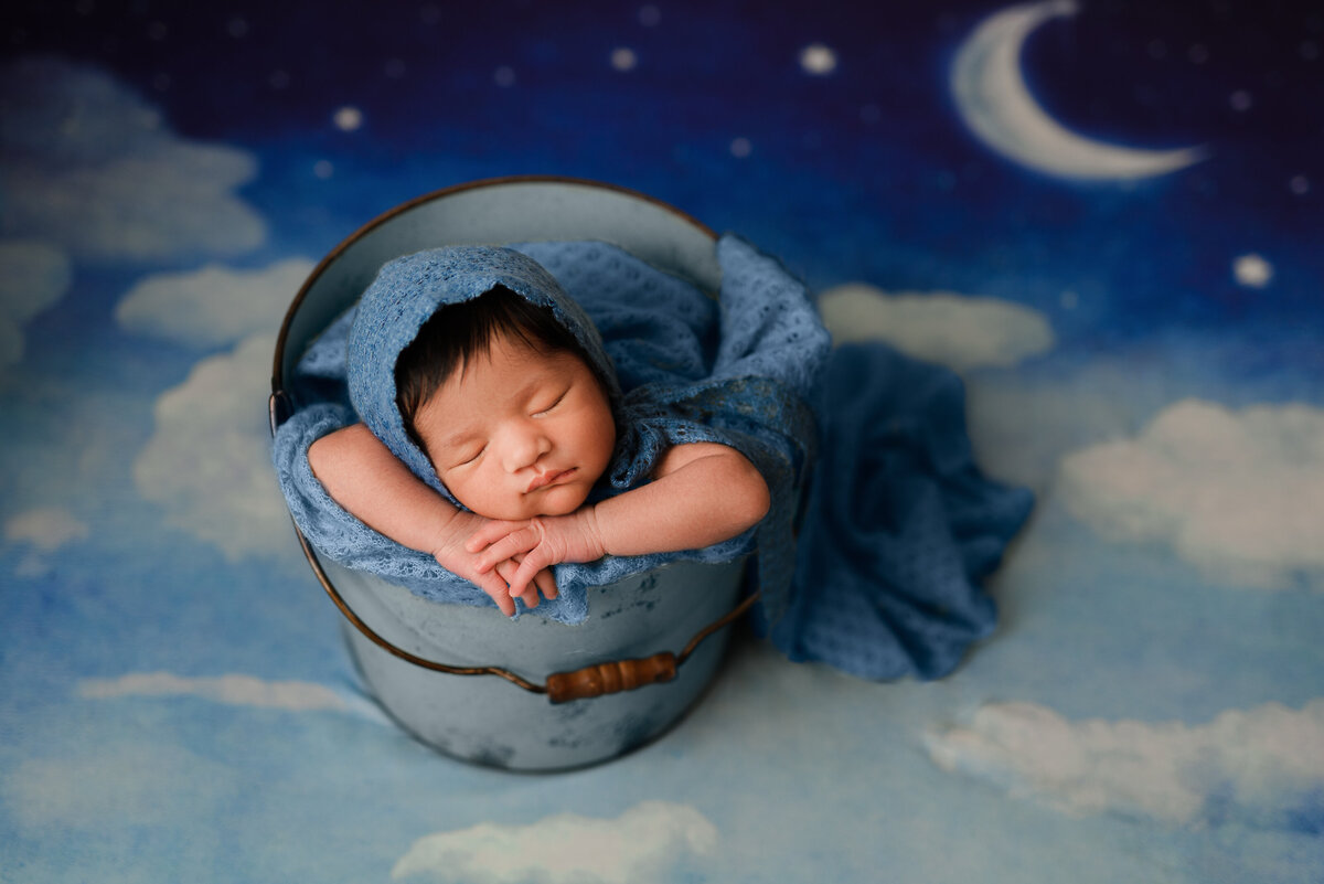 Newborn in a bucket on moon backdrop
