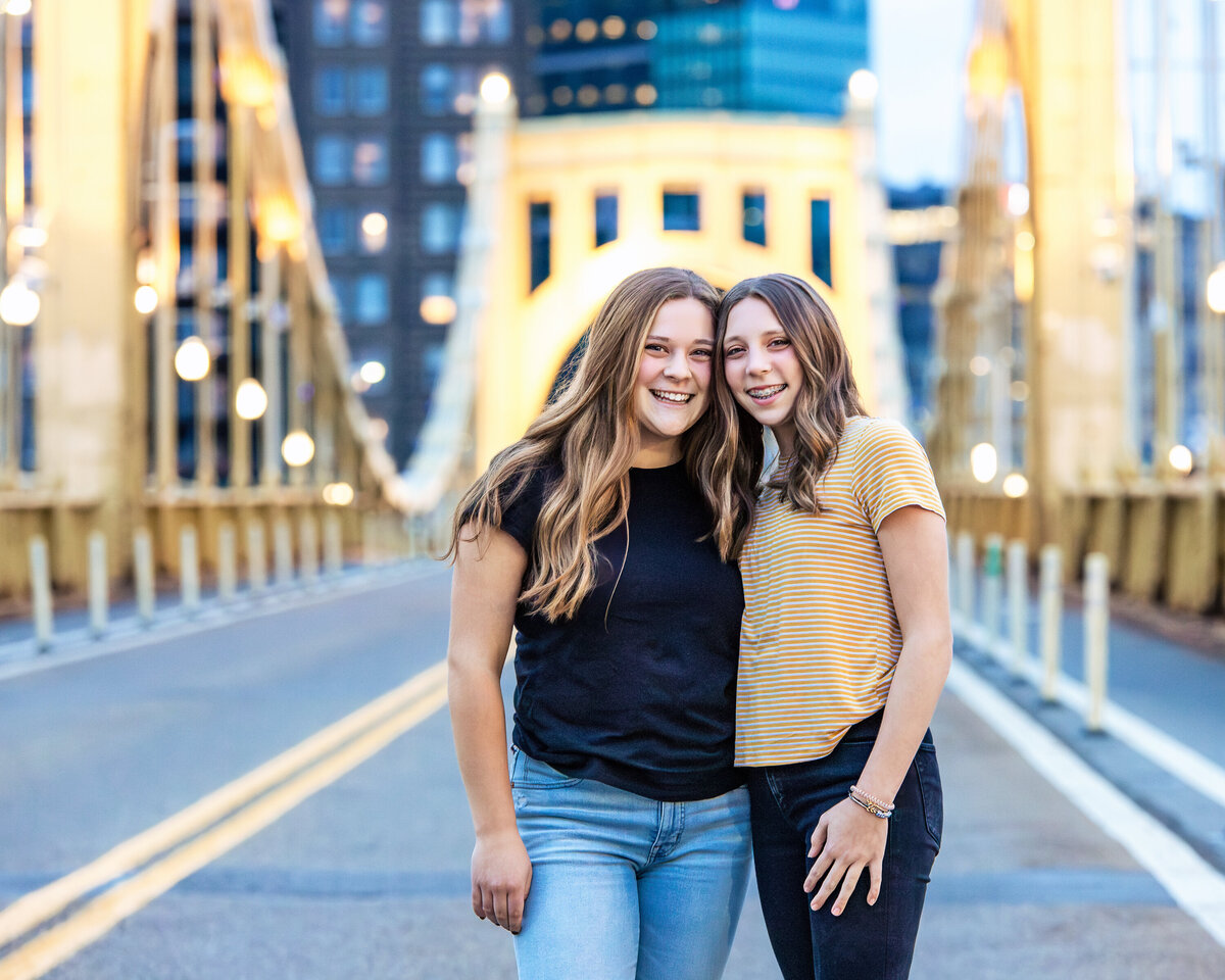 Teenaged Sister embrace on the Roberto Clemente bridge in Pittsburgh Pennsylvania during a family portrait session