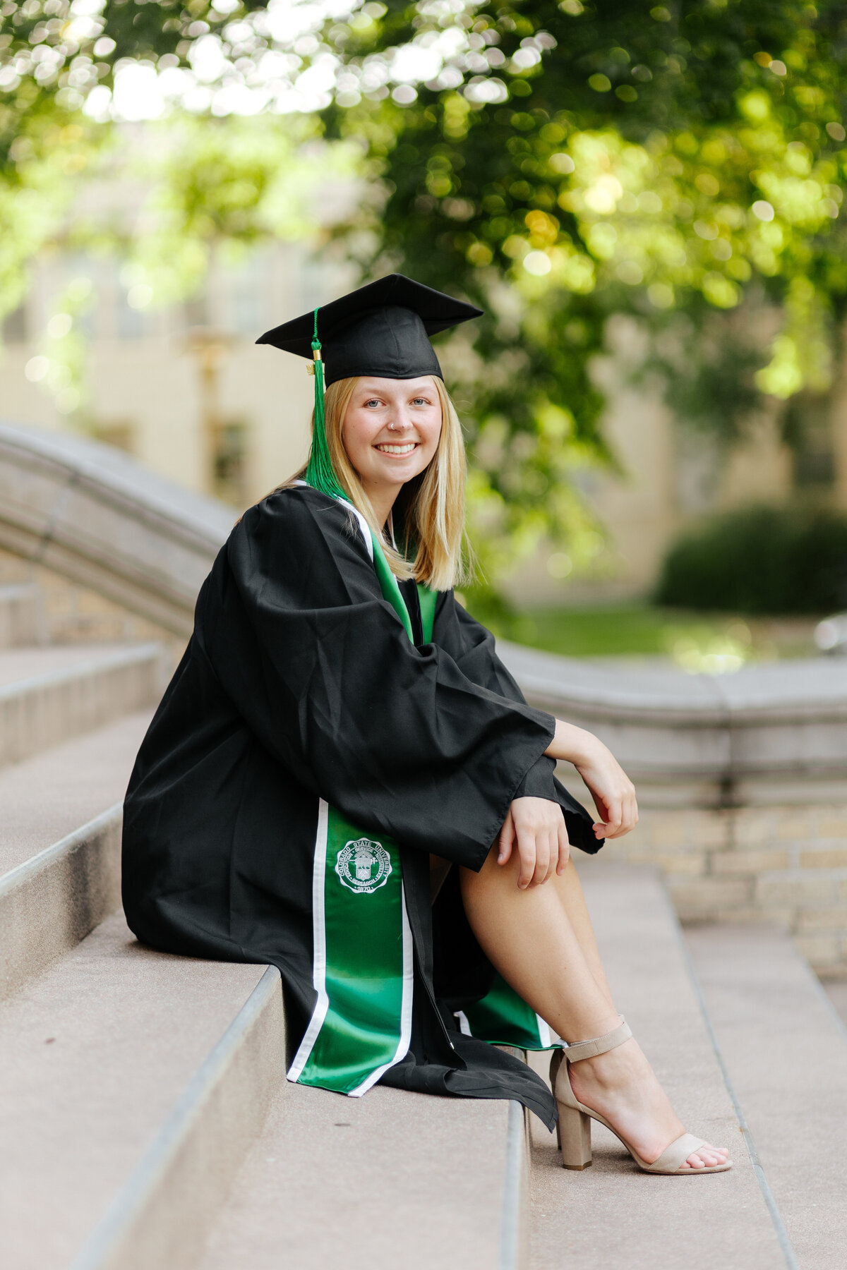 A Colorado State University graduate sits gracefully on the steps of the Administration Building during her senior grad session.