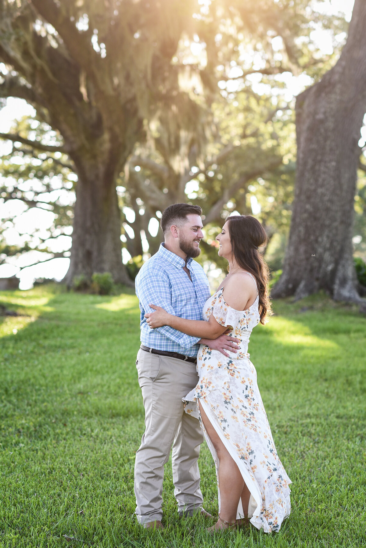 Beautiful Mississippi Engagement Photography: couple embraces at sunset under oaks with Spanish Moss in Ocean Springs, MS