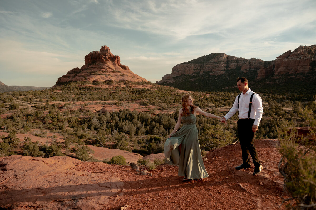 Couple standing against red rock backdrop during Sedona engagement session