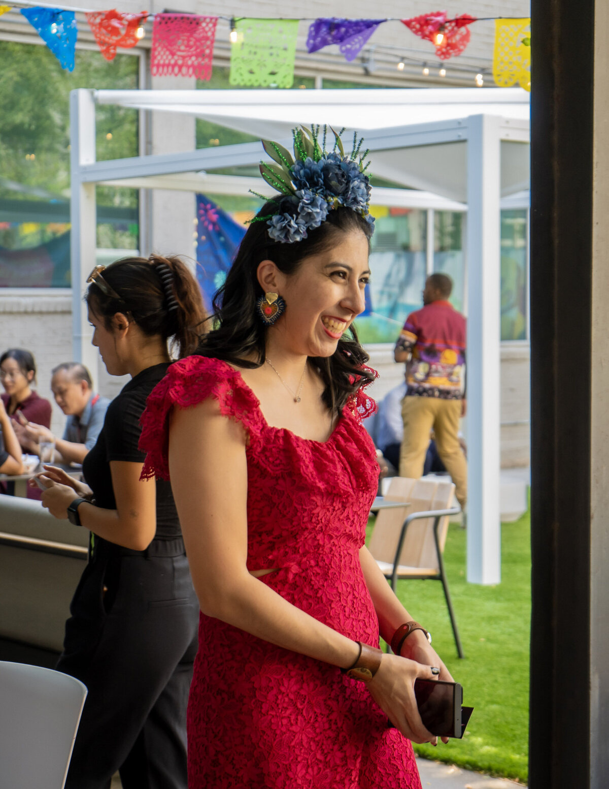 The joy of creation as Soleil Vida Studio's founder, donned in a radiant red lace dress, smiles while crafting flower crowns.