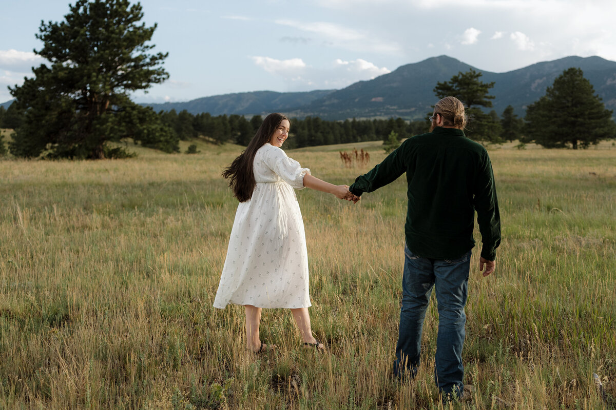 Expectant parents holding hands while walking away from the camera in Boulder CO during Maternity Session with Alexis Adkins Photography