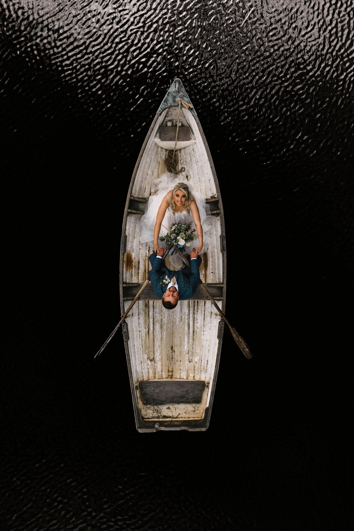 Bride and groom in a rowing boat on the lake at Wyresdale Park, Clitheroe, captured from above — showcasing a romantic and whimsical countryside wedding moment.