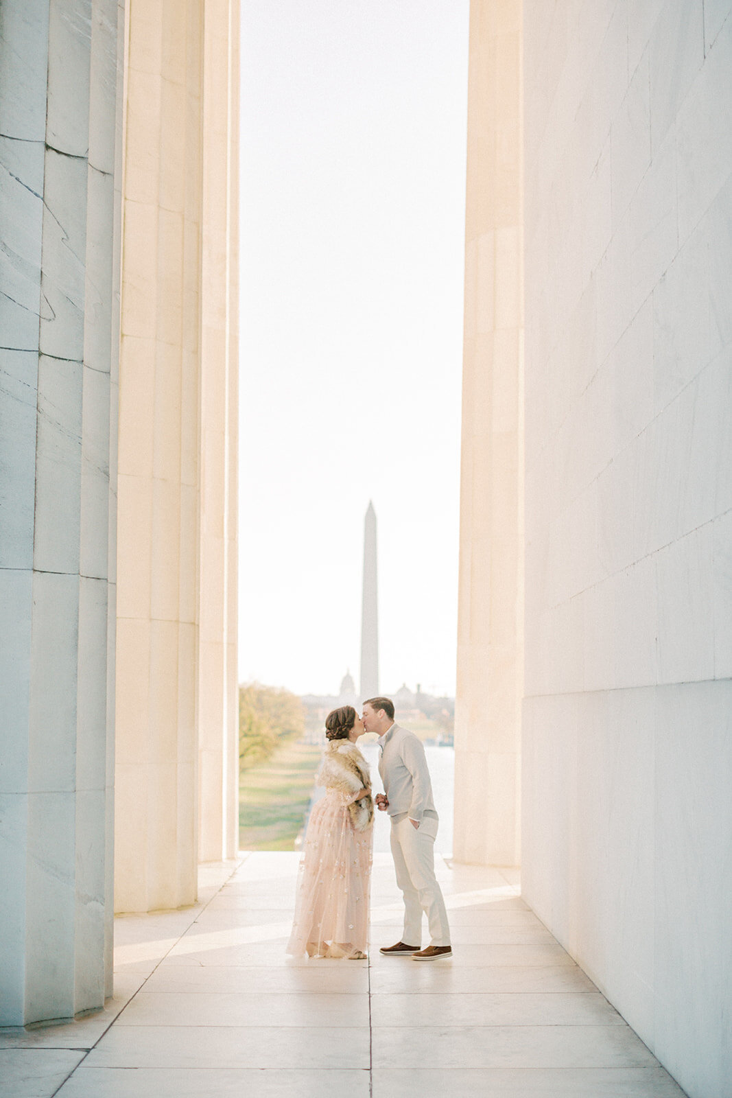 Husband and wife lean in to kiss at the Lincoln Memorial in DC during their maternity session.