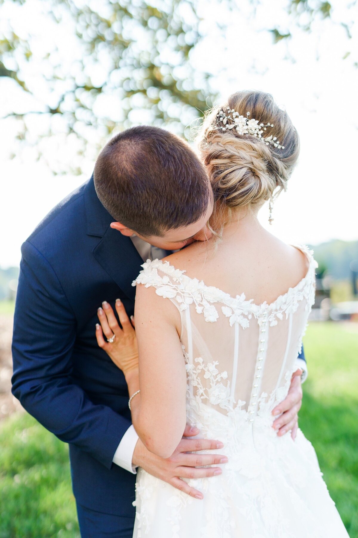 A groom kisses his bride on the neck as she snuggles into his chest at their vineyard wedding near Charlotte, NC.