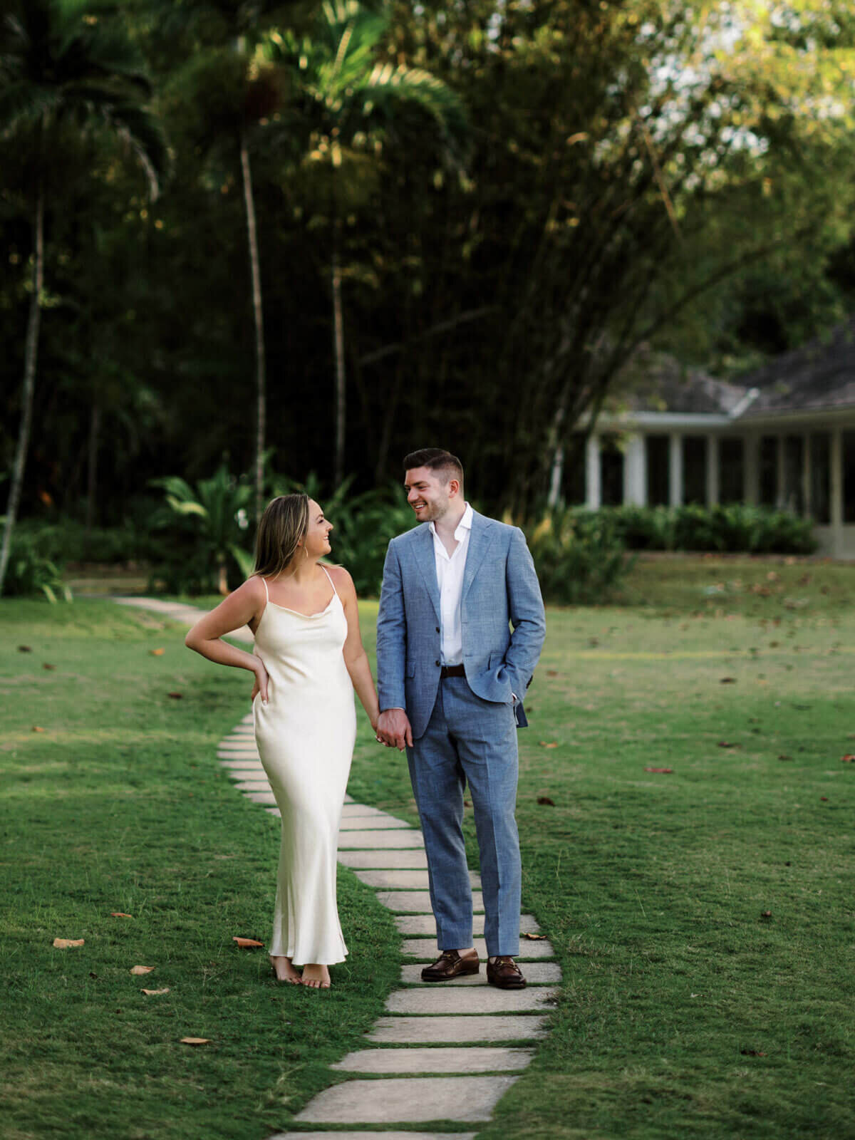 The engaged couple is walking in a trail path in the middle of the garden on Round Hill Hotel and Villas, Jamaica.