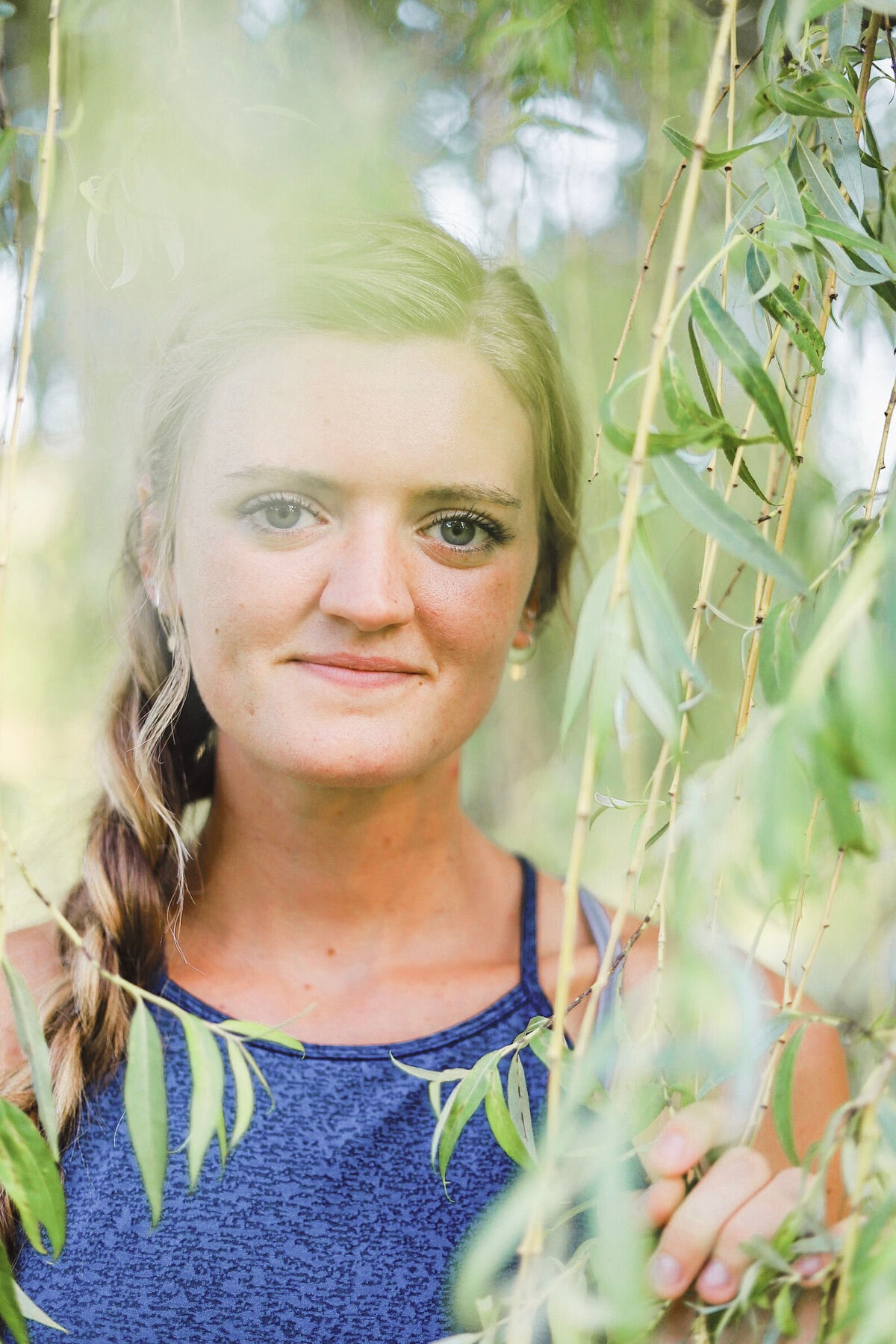 girl grinning standing in a willow tree