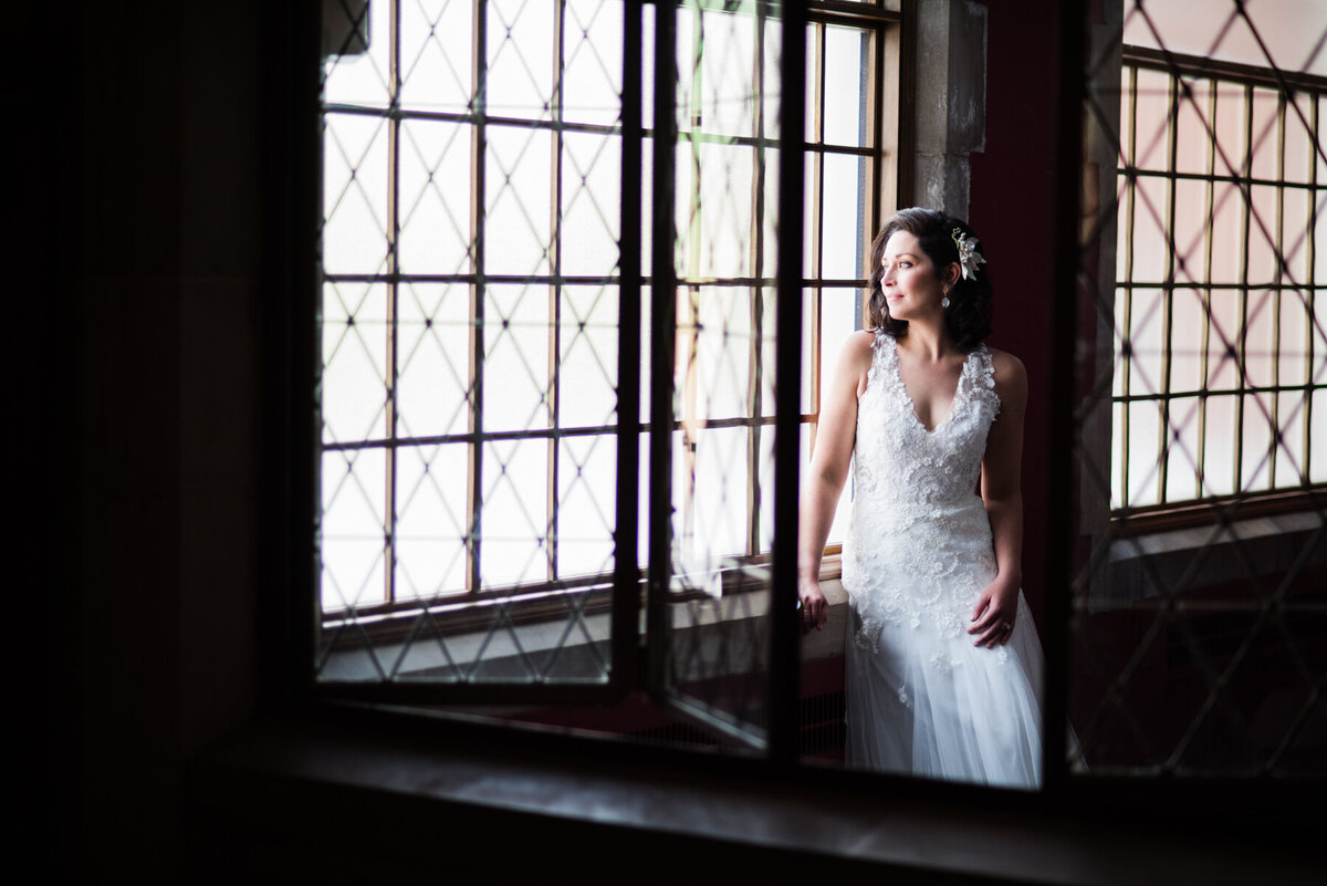 Bride looks out window at club at hillbrook