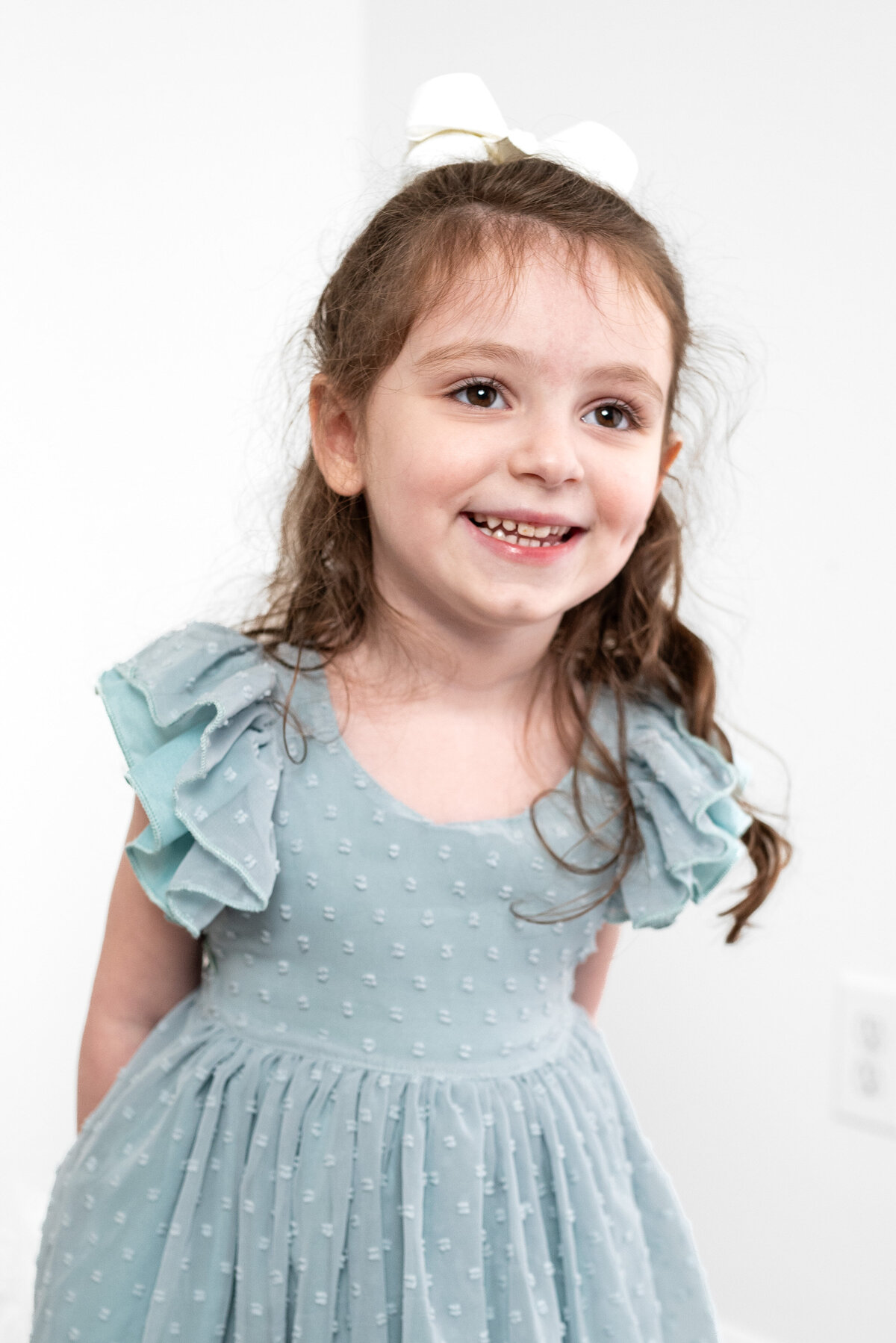 A little girl smiles at the camera for family pictures in a studio in Huntsville Alabama