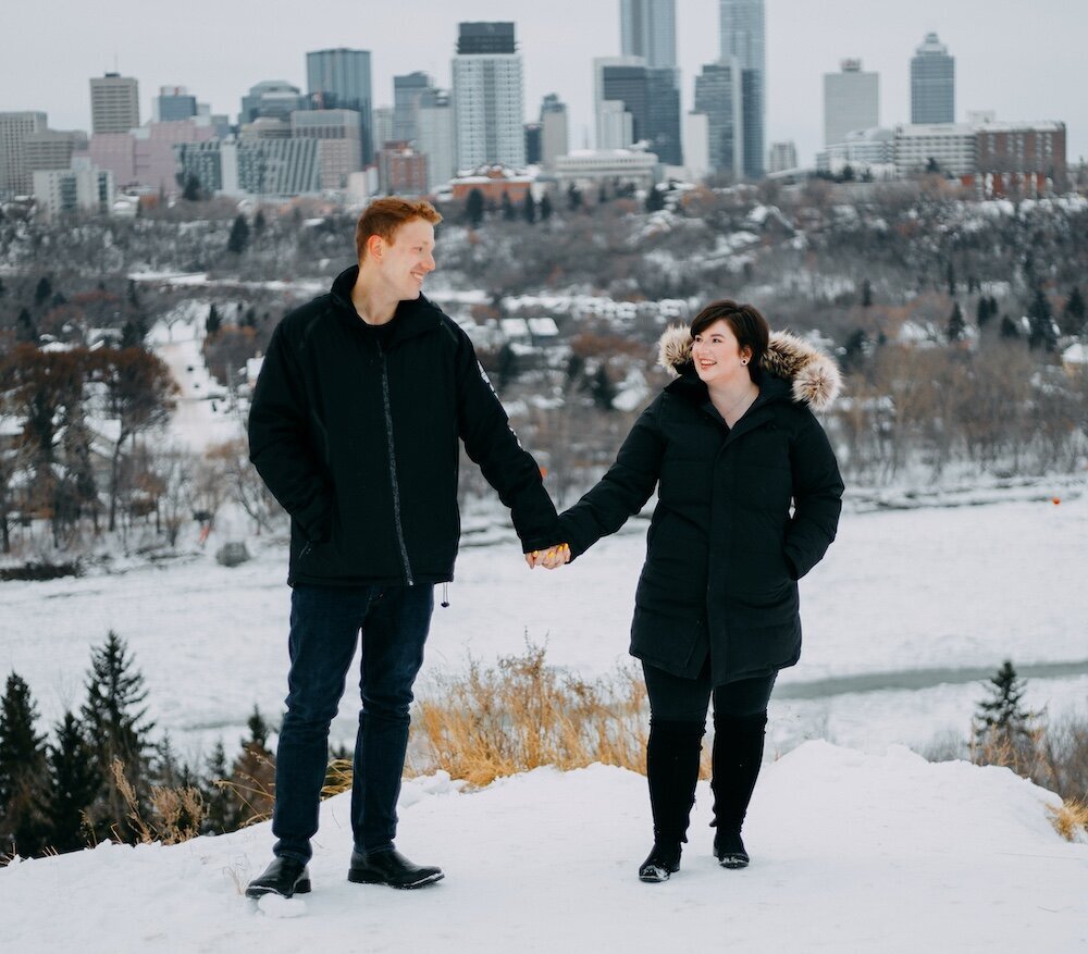 Edmonton couple hold hands in their black winter coats with snow on the ground