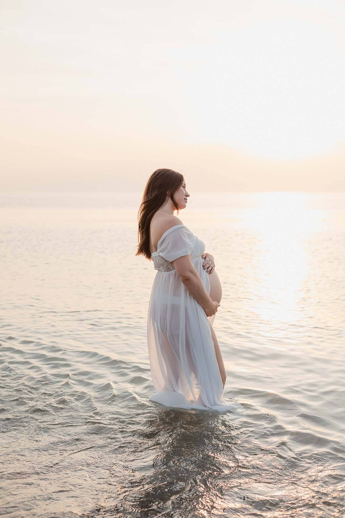 A peaceful maternity session on the beach at sunset captures the glow of an expectant mother in Cleveland.