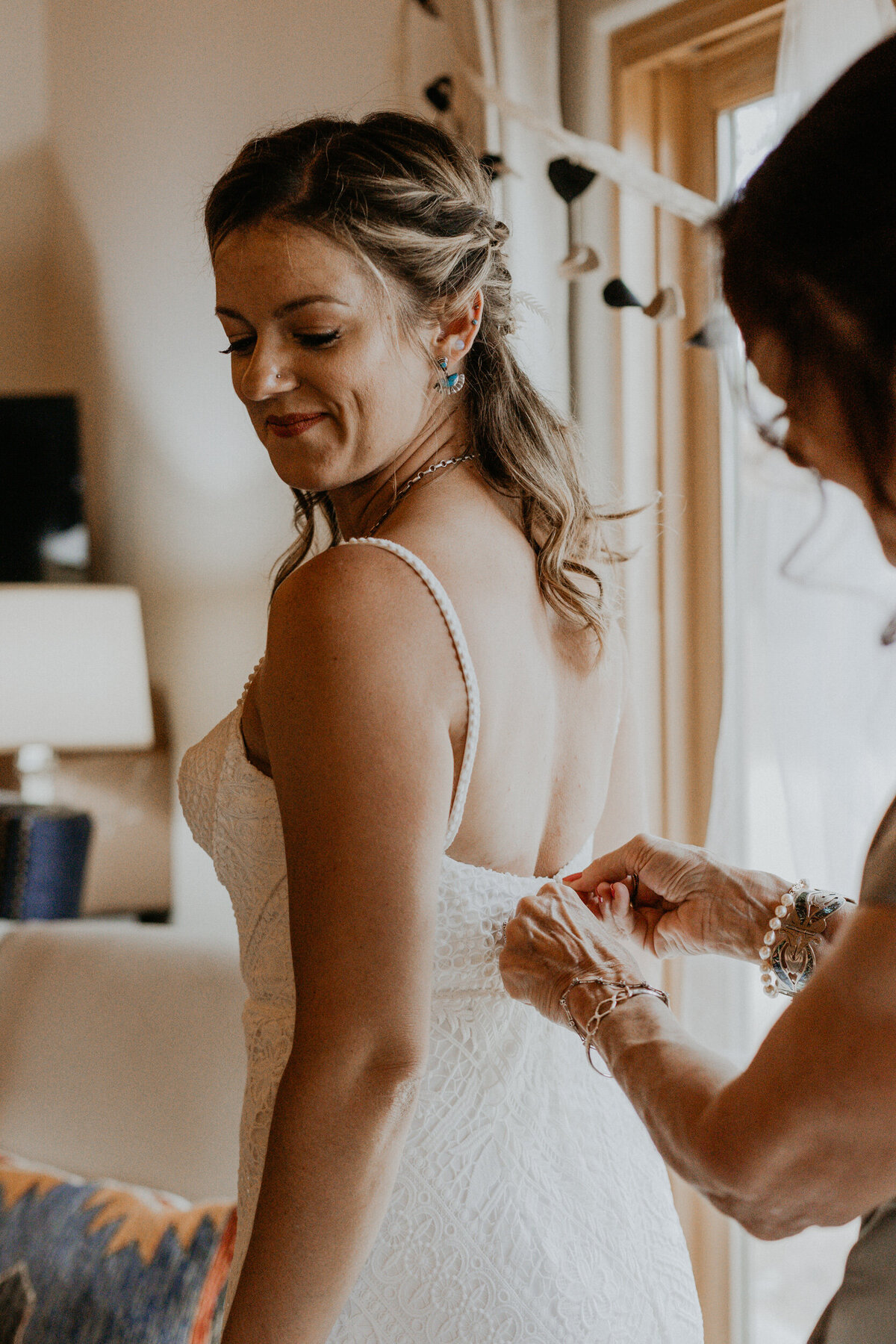 brides mom zipping up wedding dress