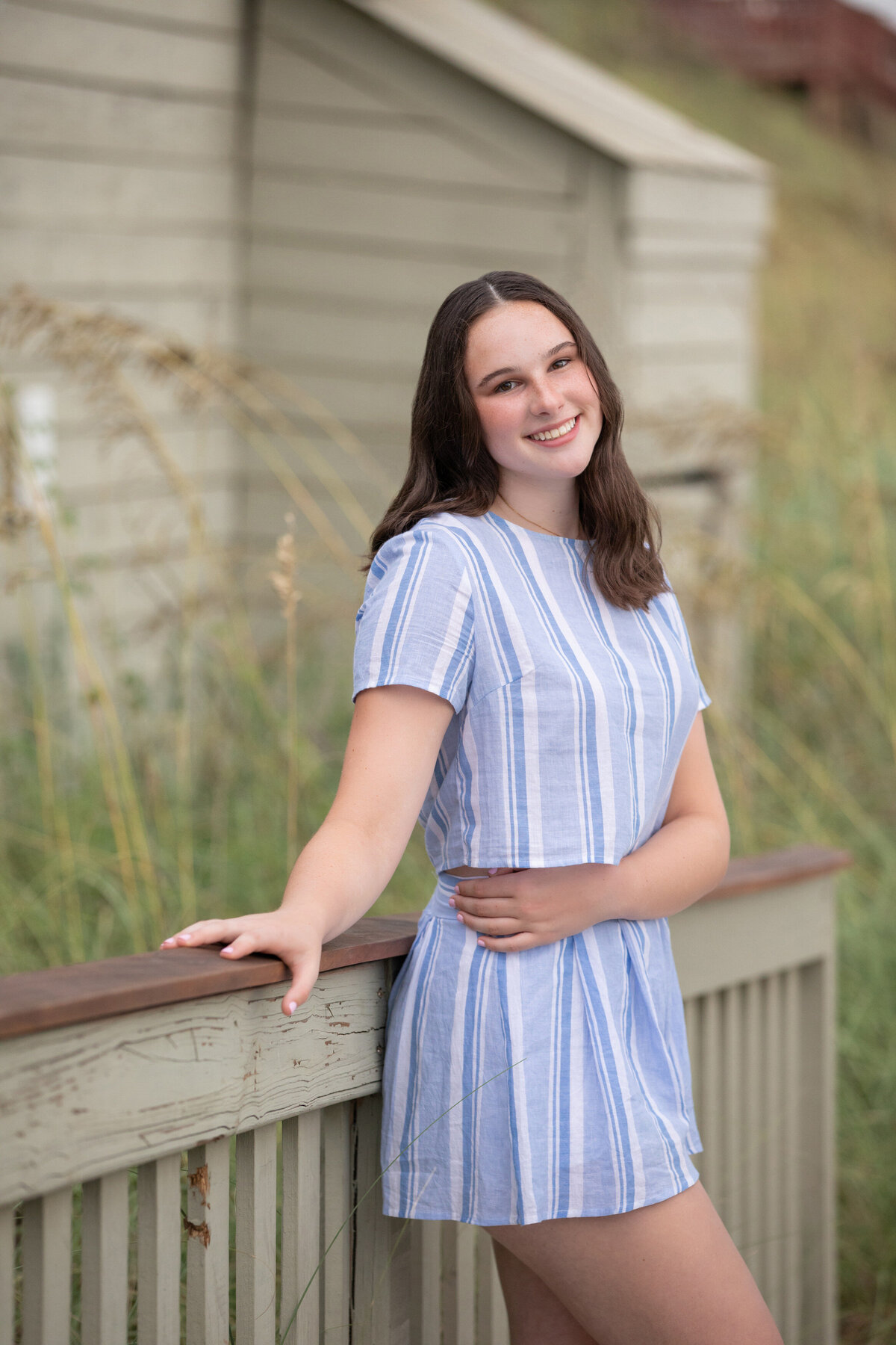 A girl leaning up against a wooden handrail