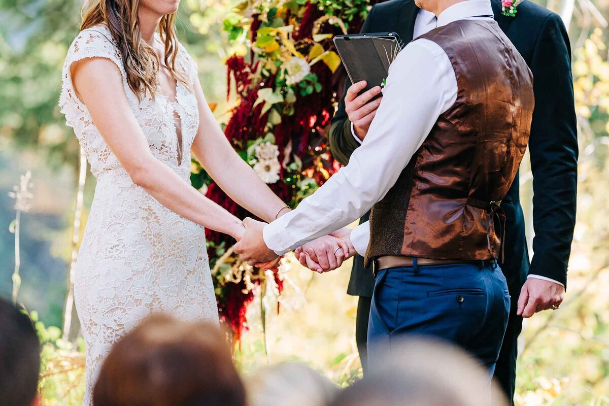 Bride and groom holding hands during wedding ceremony, Izaak Walton Inn, Essex