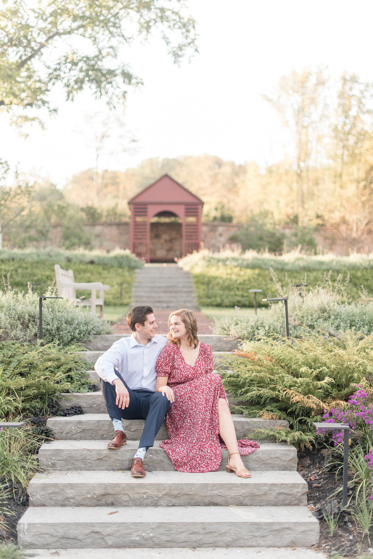 Engaged couple sitting on stone steps of garden looking at each other at Elizabeth Furnace in Lititz, Pennsylvania.