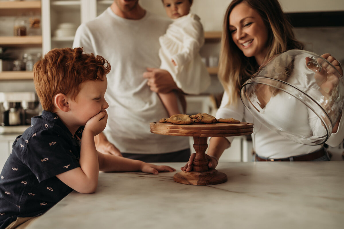 Mom surprises toddler boy with fresh baked cookies in modern updated kitchen
