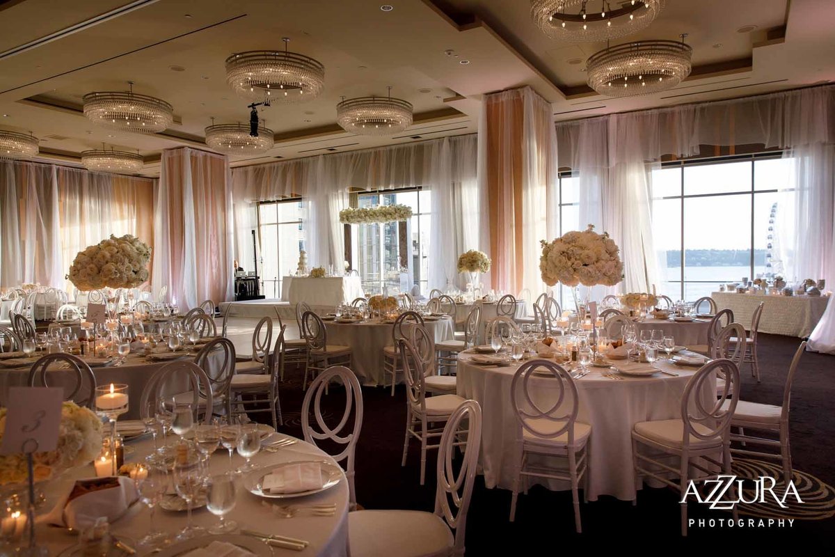 all white wedding with round reception tables in white linens, white chairs, white flowers