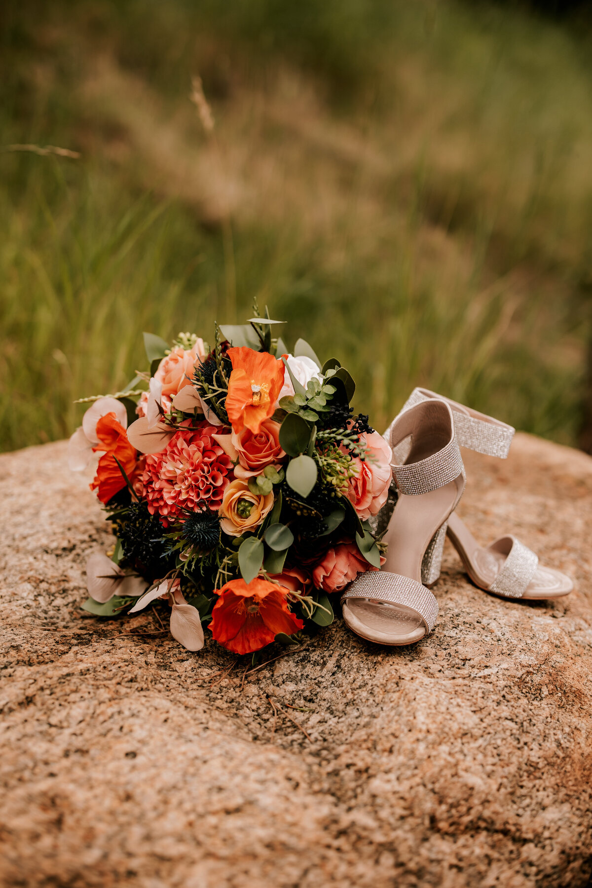 Detail photo of brides bouquet and gold shoes perched on a rock