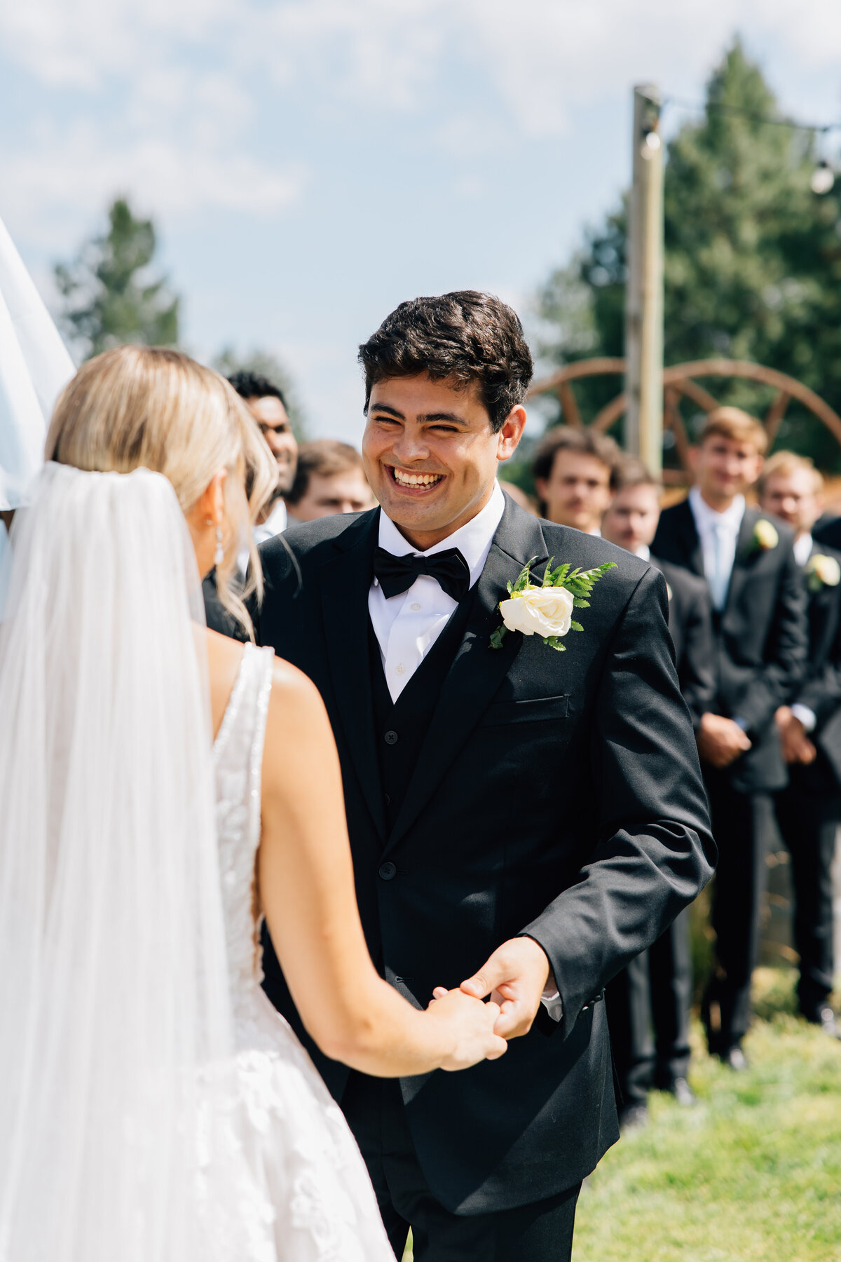 Groom smiles at his bride while he holds her hand on their coeur d'Alene wedding day ceremony 