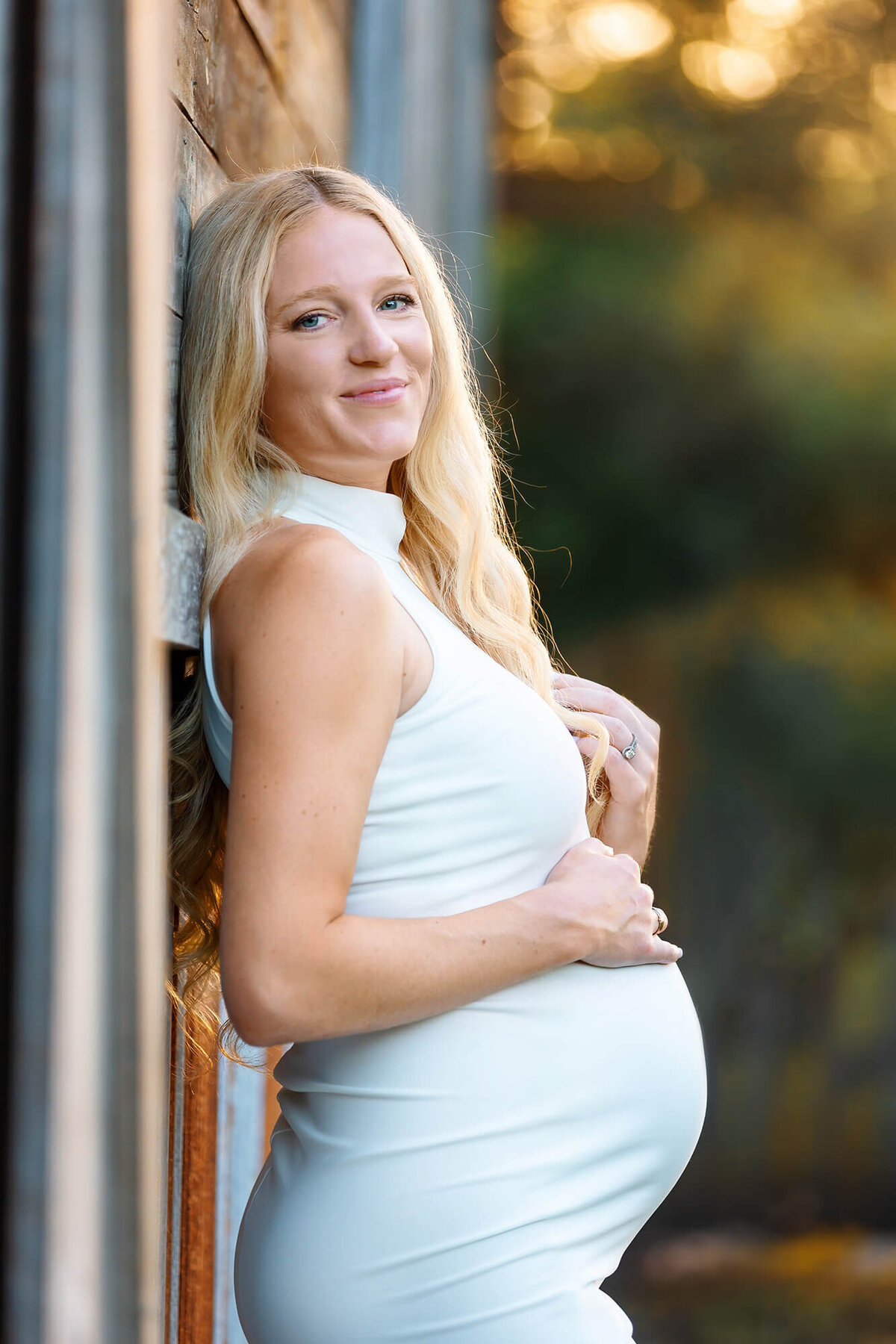 Stunning pregnant woman wearing a white dress photographed near a barn by Lake Jackson photographer Danielle Dott.