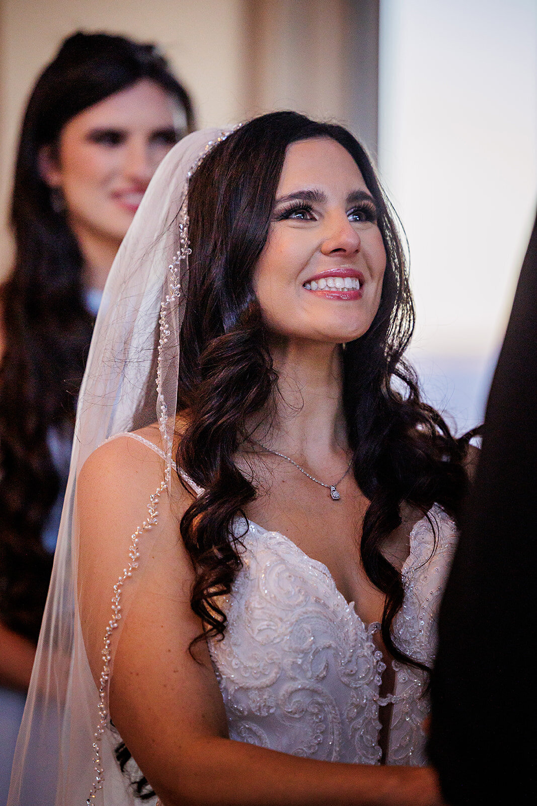 Bride in a beaded  veil  looks at her groom.