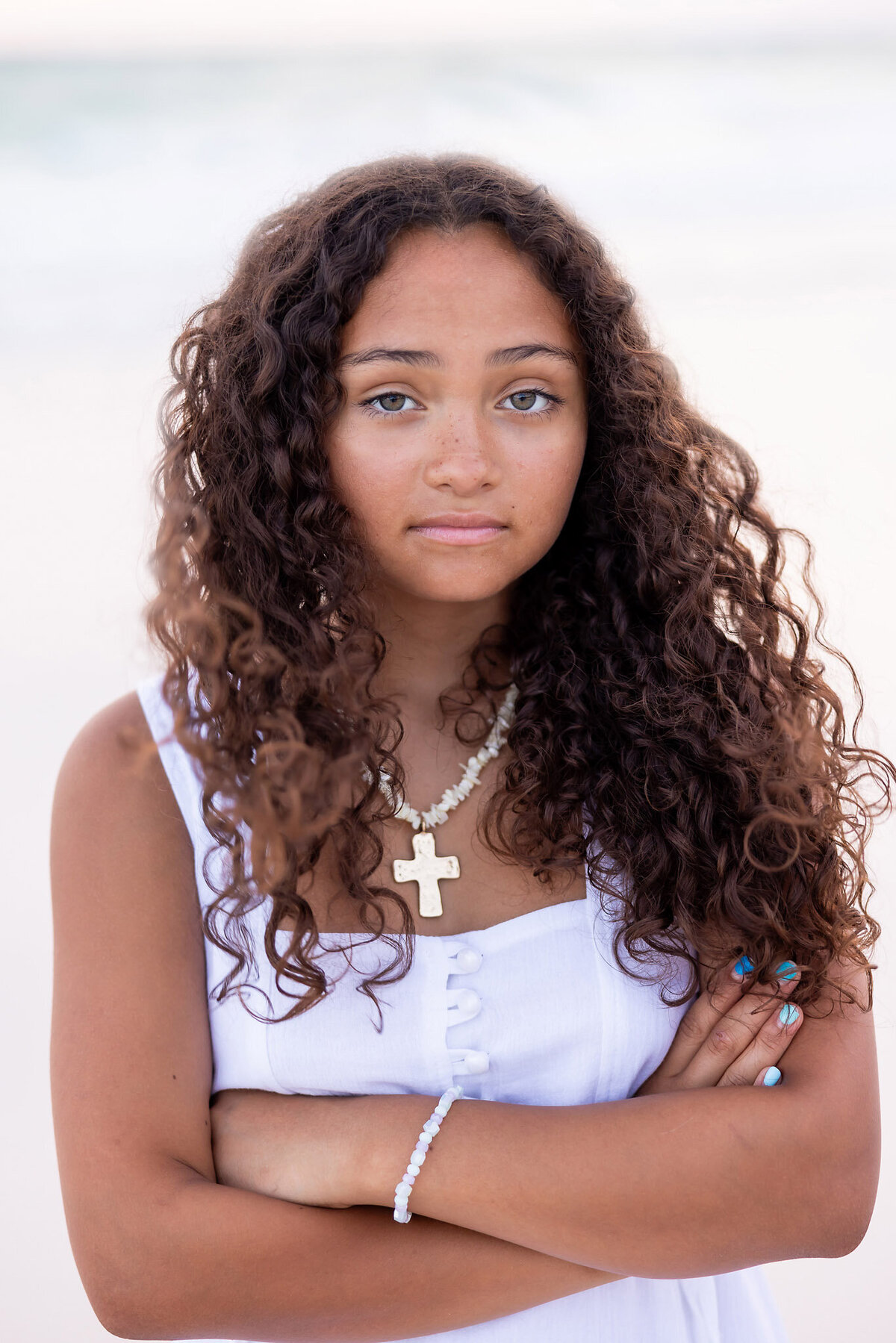 closeup of a teenage girl with beautiful curls and eyes on the beach in front of Adagio on 30a.