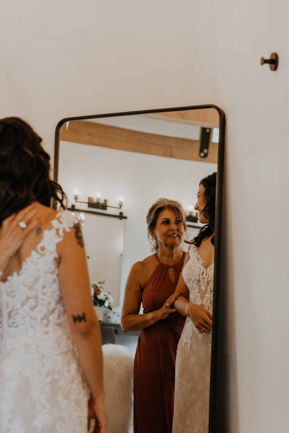 bride and her mom getting  in her wedding dress