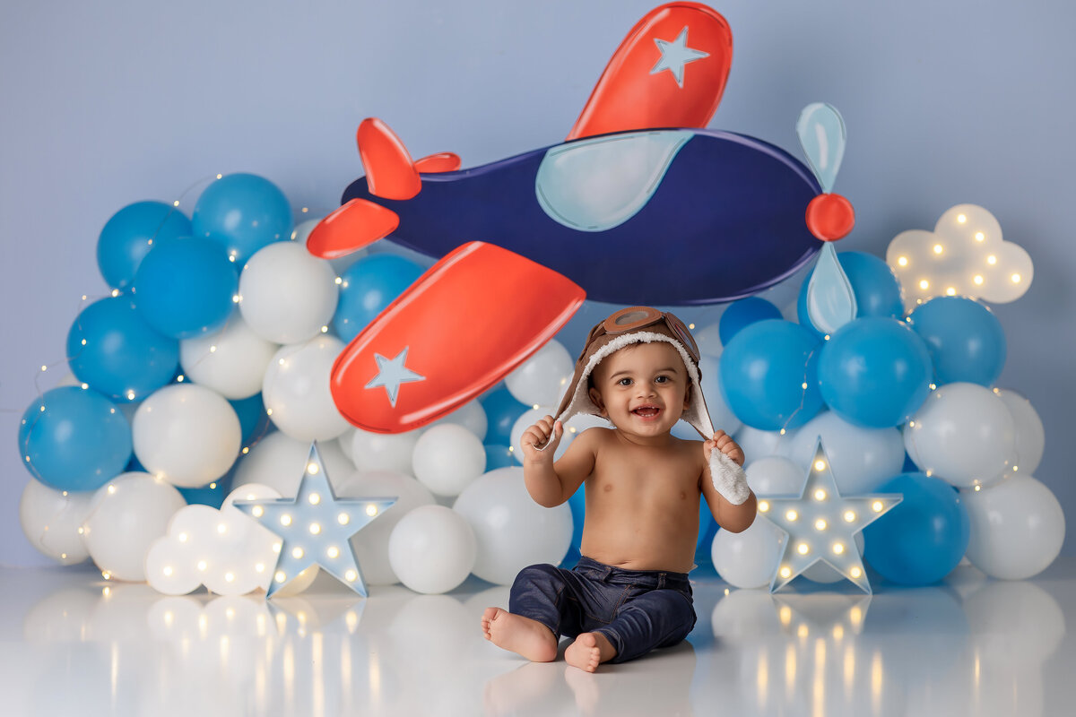 One year old Tampa baby enjoying a personalized luxury cake smash session with playful airplane decorations