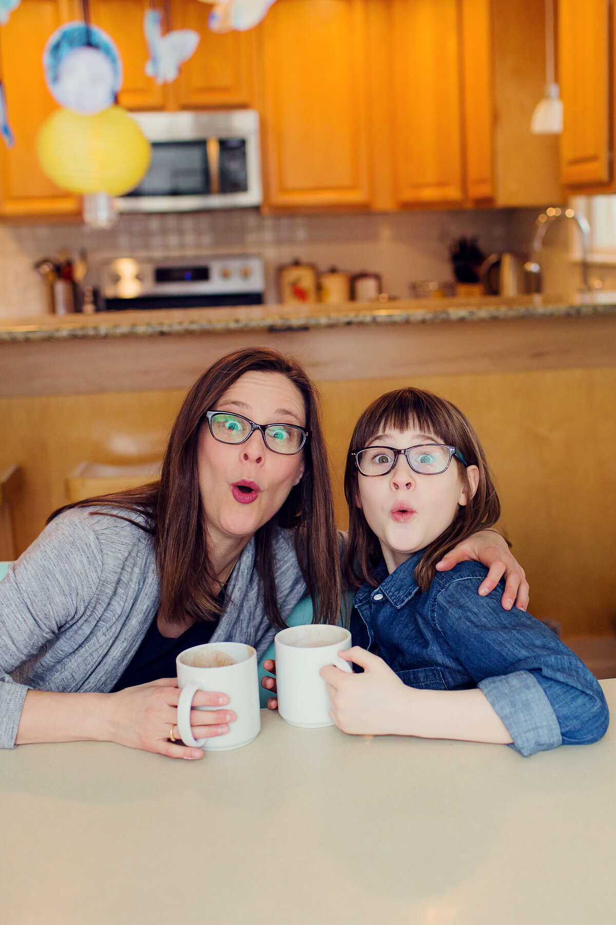 Mom in gray and daughter in blue make a silly, surprised face at the end of their photo session.