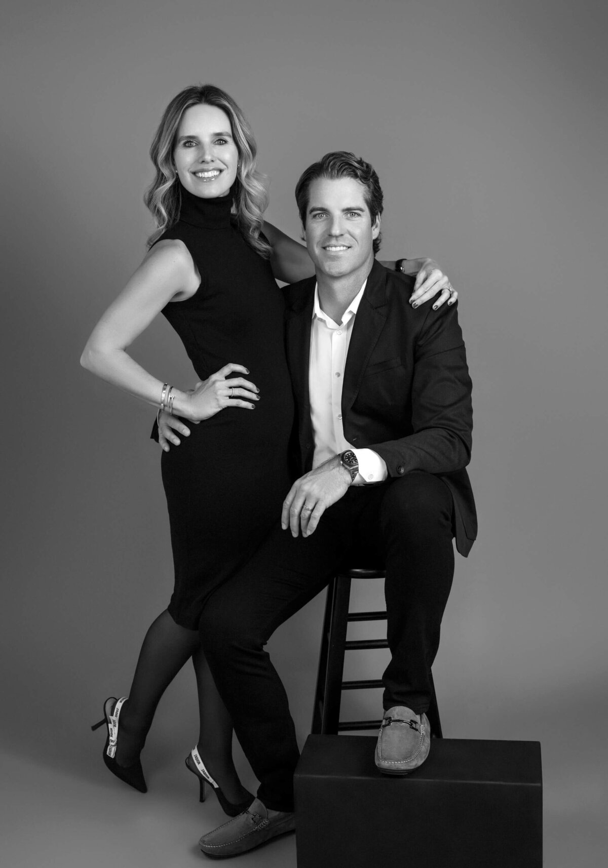 Black and white studio portrait of a stylish couple, dressed in formal wear.