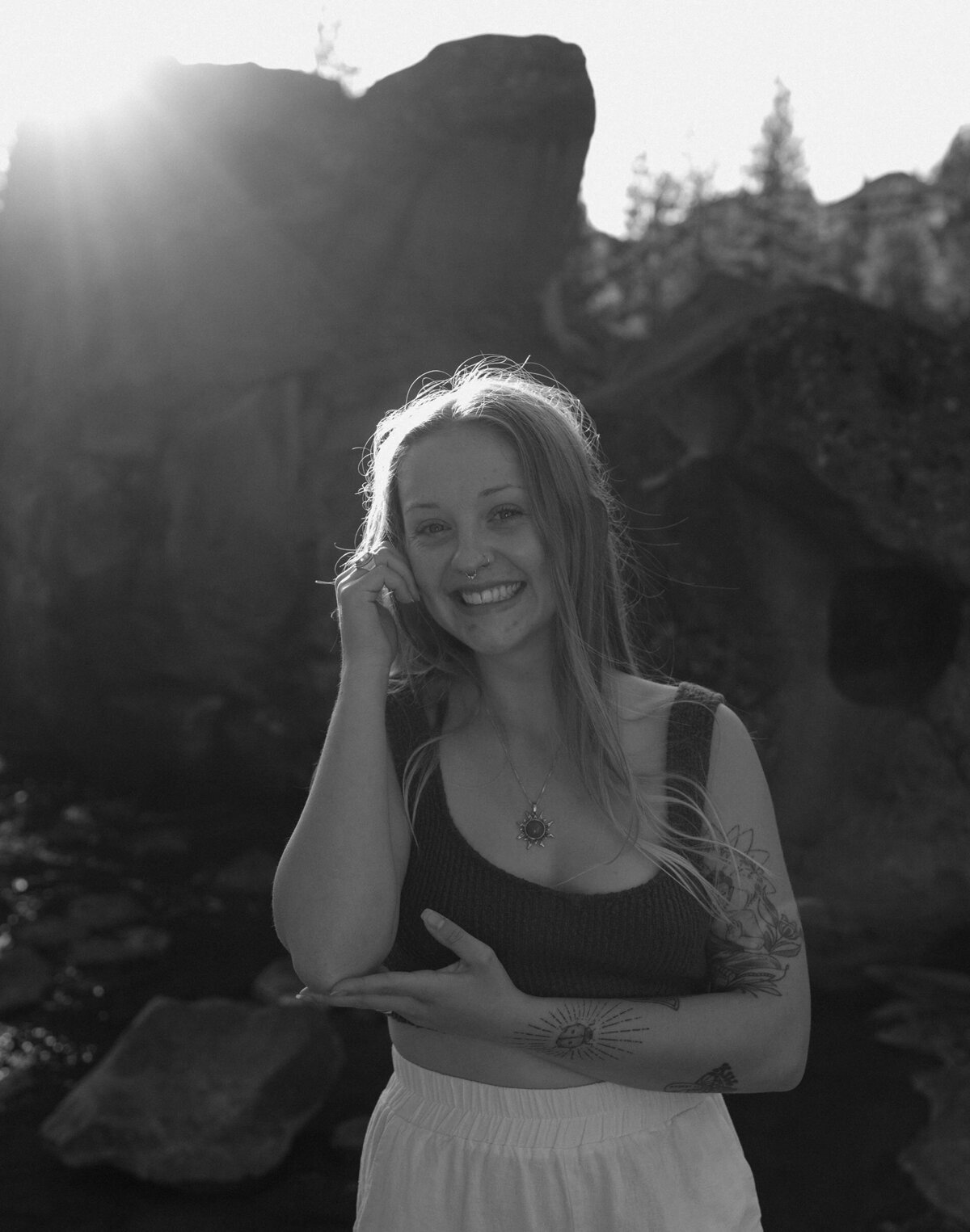 woman playfully smiles and poses for the camera while standing near the river in central Oregon