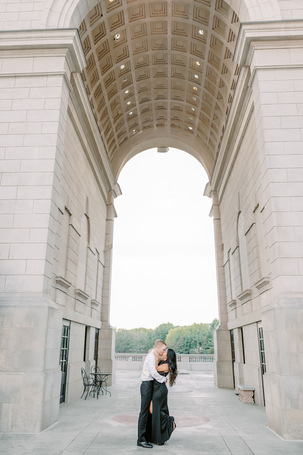 Man kisses woman in black dress under Millennium Archway